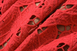 Close-up detail of red lace fabric with a matching invisible zipper on dress back