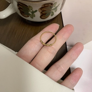 Vue détaillée d'une bague texturée dorée avec sept petites perles sur un doigt
