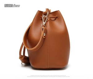 Profile view of brown PU leather bucket bag with tassel details and golden hardware
