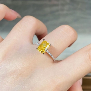 Macro shot of a rectangular radiant cut yellow gemstone ring on a female finger