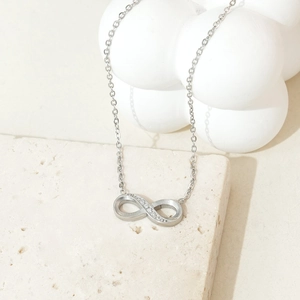 Detail of silver infinity necklace featuring pavé zircon accents on a textured stone base
