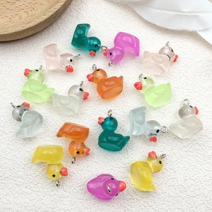 Close-up of colorful translucent resin ducks with metal rings on white fabric