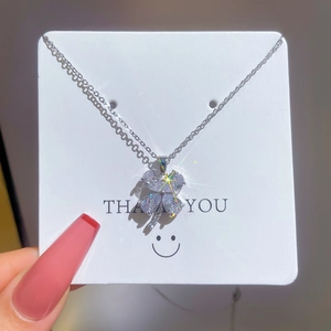 Silver four-leaf clover necklace with sparkling micro-pave crystals on a white card