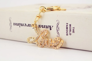 Close-up of golden metal LOVE keychain with sparkling rhinestones on an open book