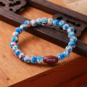 Close-up of sports style beaded bracelet with red and blue beads and a rugby shaped focal
