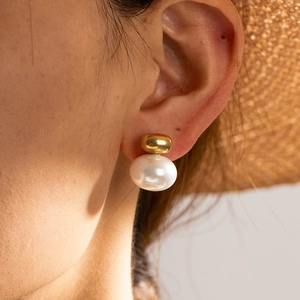 French vintage style gold metal sphere and teardrop pearl drop earrings worn by a model