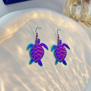 Macro detail of iridescent sea turtle drop earrings with colorful metallic finish