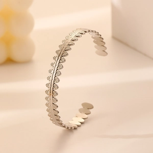 Detail of silver stainless steel open bangle featuring continuous leaf pattern engraving