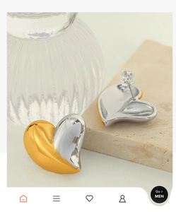 Détail des boucles d'oreilles cœur bicolores or et argent sur texture minérale