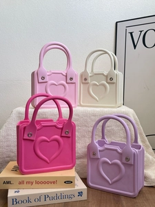 Detailed view of square EVA beach handbags in pink and purple with heart relief pattern