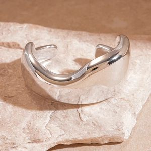Detail view of silver wavy acrylic cuff bracelet on a natural stone surface