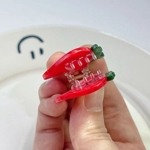Detail of a mini strawberry claw clip with vibrant red acrylic and green leaf accents