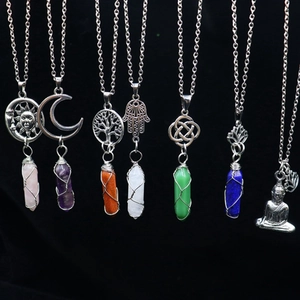 Macro shot of assorted crystal pendants with moon and tree of life silver charms on black background