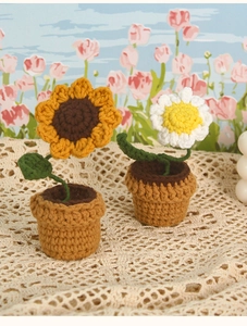 Detail of handmade crochet sunflower and daisy potted plants on lace fabric surface