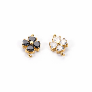 Detailed view of four-leaf clover charms in black and white with gold prong setting