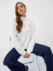 Detail of red heart embroidery logo on white half-zip fleece sweatshirt with collar