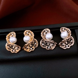 Macro detail of 18K gold plated flower earrings with pearls and crystals on black velvet