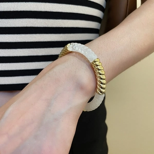 Detailed close-up of acrylic and gold rope metal linked bracelet on woman's wrist