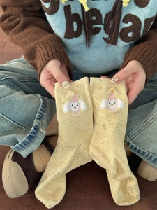 Detail of yellow cotton socks with colorful speckled yarn and cartoon embroidery