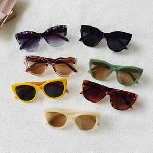 Modern small frame sunglasses in multiple colors displayed on white textured sand background