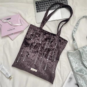 Flat lay of velvet tote bag with pearl embroidery and silver stitch detailing