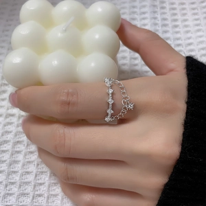 Close-up of double-layer silver ring featuring star pendant and zircon pavé on finger