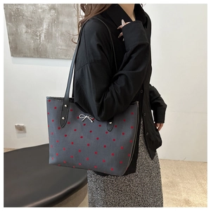 Nahaufnahme einer dunkelgrauen gepunkteten Totebag mit silberner Schleife am Modell