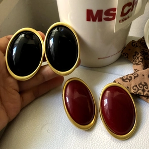 Detail of vintage oval stud earrings in deep red and black with gold metal frames