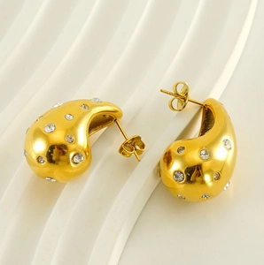 Detail of 18K gold teardrop earrings with sparkling zircons on wave background