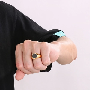 Close-up of men's polished gold titanium ring with a round black enamel centerpiece