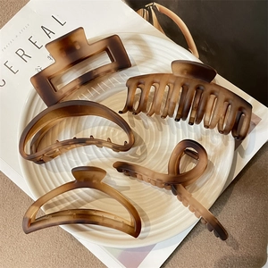 5-piece set of matte amber brown hair claws in various shapes on a ceramic plate