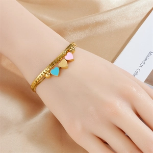 Double-layer gold chain bracelet with three colorful enamel heart charms on silk backdrop