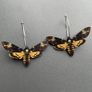 Macro shot of colorful hawkmoth earrings with skull patterns and silver metal hooks