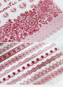 Macro detail of dark red lace nail stickers with floral mesh and scrollwork patterns