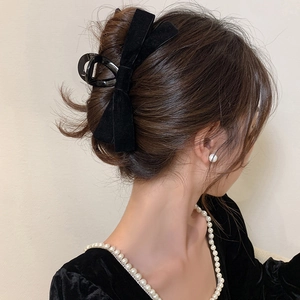 Detail of elegant black velvet bow hair claw clip worn on model's head for styling