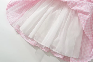 Detailed close-up of pink plaid dress hem with white tulle lining layer
