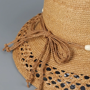 Detail eines Raffia-Sonnenhuts mit gewebter Schleife, weißen Perlen und Netzkrempe