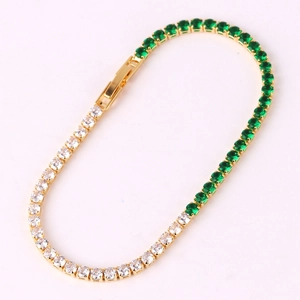 Elegant gold bracelet with emerald green and white zircon stones on a pink background