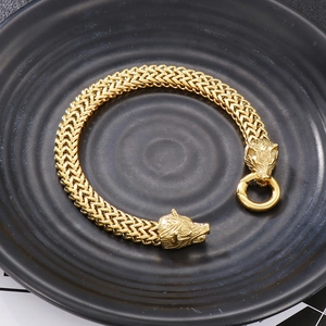 Mens gold wolf head woven bracelet in punk hip hop style on black textured background