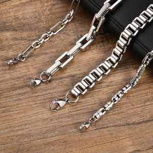 Detail view of four silver stainless steel chains with lobster clasps on wood
