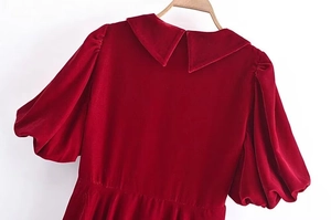 Détail d'une robe en velours rouge avec manches bouffantes et col Peter Pan
