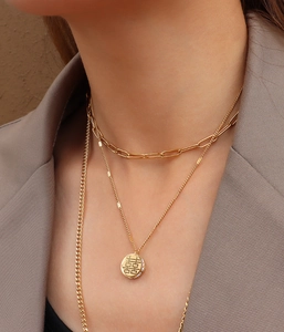 Gros plan d'un collier doré multicouche avec pendentif Double Bonheur serti de zircons
