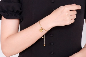 Close-up of golden Love heart pendant bracelet on model with black dress background