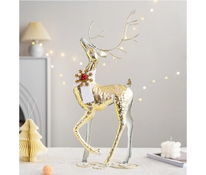 Close-up of golden Christmas reindeer statue with white scarf and red berry details