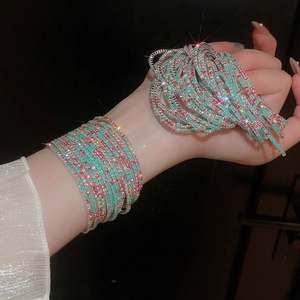 Detail of stacked multi-layer crystal stretch bracelet in mint green and magenta tones