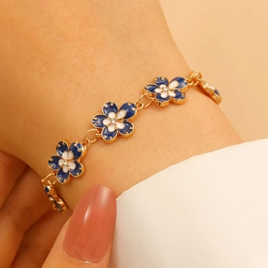 Detail of vintage gold flower bracelet with blue and white petals on wrist