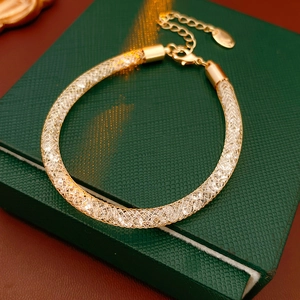 Détail du bracelet en maille dorée avec zircon sur une boîte à bijoux vert foncé