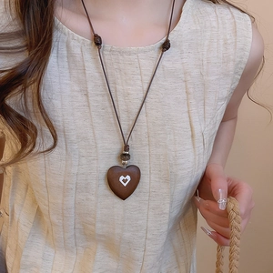 Detail of vintage wooden heart pendant with dark beads on ethnic style rope necklace