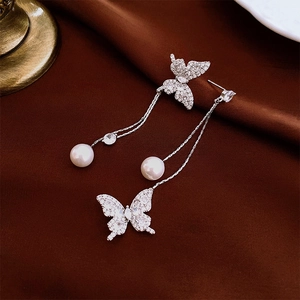 Detail of silver butterfly earrings with tassel chain, zircon pavé and pearl drops