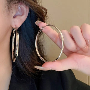 Close-up of large polished silver geometric hoop earrings with sparkling diamond inlays